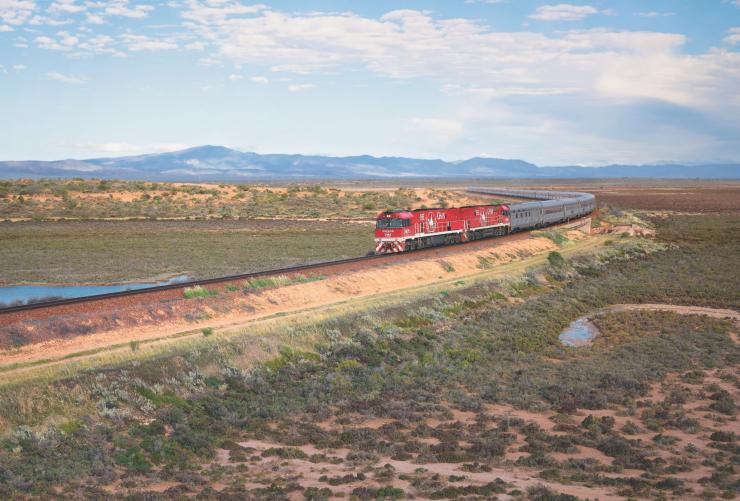 Kereta merah melintasi dataran hijau, The Ghan, Port Augusta, South Australia © Journey Beyond