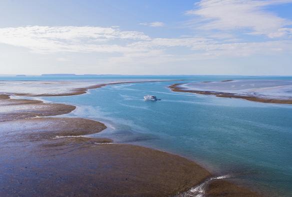 Kapal pesiar melewati karang laut yang mencuat, Montgomery Reef, Kimberley, Western Australia © Garry Norris Photography