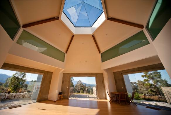Bagian interior ruangan yoga yang diterangi cahaya, lengkap dengan jendela besar dan jendela atap heksagonal menghadap ke pepohonan di luar di Harmony Hill Health Retreat, Hobart, Tasmania © Harmony Hill Health Retreat