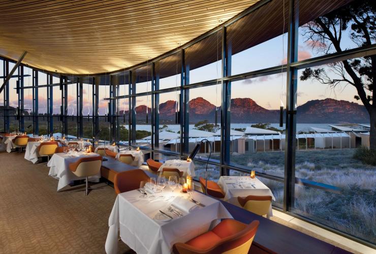 Interior Palate Restaurant, dengan meja-meja yang berjejer di sepanjang jendela setinggi langit-langit dengan pemandangan Freycinet National Park di Saffire Freycinet, Coles Bay, Tasmania © Saffire Freycinet