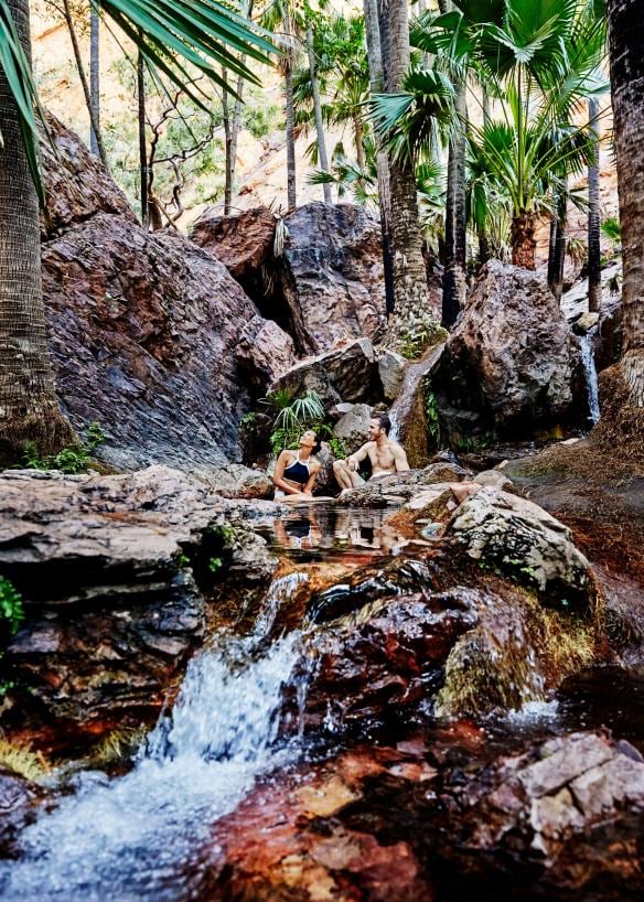 Sepasang kekasih sedang bersantai di tengah air terjun Zebedee Springs, El Questro Wilderness Park, Western Australia © Tourism Western Australia