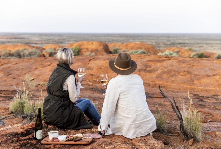 Pasangan meminum anggur dan mengagumi pemandangan outback di Wooleen Station, Golden Outback, Western Australia © Tourism Australia