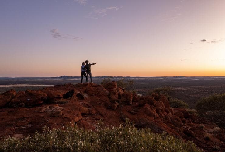 Pasangan mengagumi pemandangan outback saat matahari terbenam di Wooleen Station, Golden Outback, Western Australia © Tourism Australia