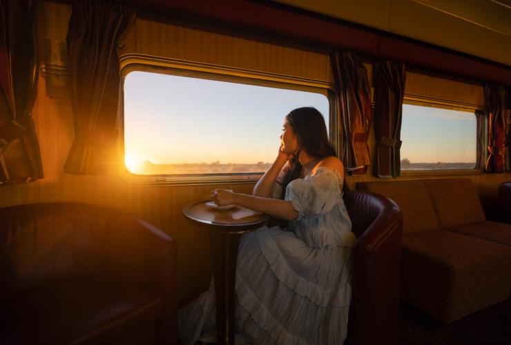 Seorang wanita menikmati minuman hangat di atas kereta The Ghan, Northern Territory © Tourism Northern Territory/Daniel Tran