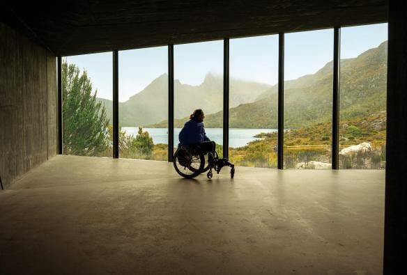 Una persona su una sedia a rotelle che ammira un panorama mozzafiato dal punto di osservazione riparato di Dove Lake, Cradle Mountain-Lake St Clare National Park, Tasmania © Tourism Australia