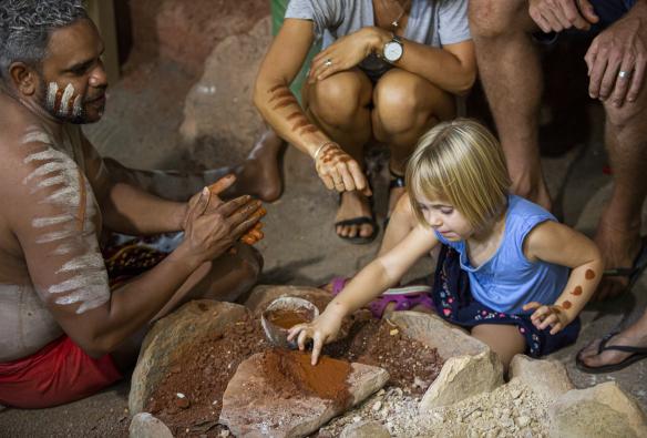 Una famiglia che si dipinge le braccia con l'ocra insieme a una guida aborigena locale con il corpo decorato con la tecnica tradizionale del body painting presso il Rainforestation Nature Park durante la Pamagirri Aboriginal Experience, Kuranda, Queensland © Artra Sartracom