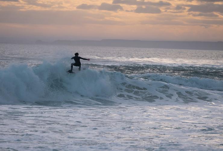Surfista che cavalca un'onda al tramonto a Cape Woolamai, Phillip Island, Victoria © Tourism Australia