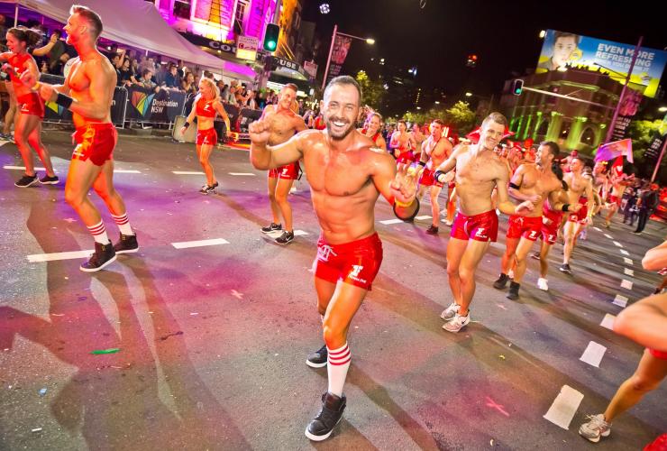 Gruppo di persone che indossano abiti rossi e che ballano in sincronia per le strade di notte durante il Sydney Gay and Lesbian Mardi Gras, Sydney, New South Wales © Hamid Mousa