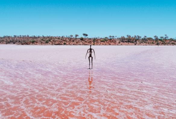 Una scultura in metallo che raffigura una persona in piedi in un lago rosa, Lake Ballard, Menzies, Golden Outback, Western Australia © Australia’s Golden Outback