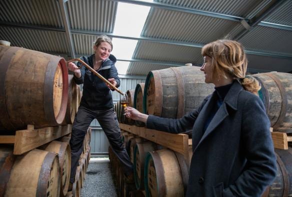 Un membro del personale che versa un liquore di colore ambrato da una botte nel bicchiere di un ospite alla Lark Distillery, Hobart, Tasmania © Tourism Australia