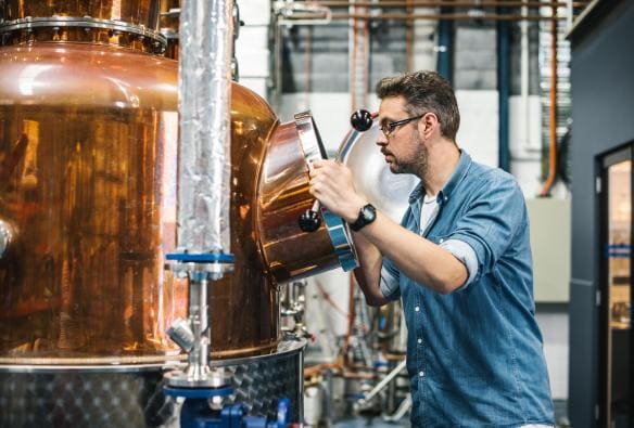 Membro del personale che valuta l'andamento del processo di distillazione di liquori da Manly Spirits Co., Manly, New South Wales © Alana Dimou