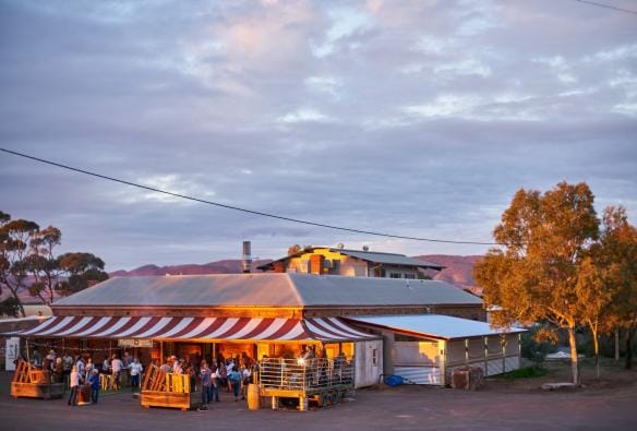Persone riunite all'esterno di un pub dell'outback con veranda a righe bianche e rosse al Prairie Hotel, Flinders Ranges & Outback, South Australia © South Australian Tourism Commission/Tourism Australia