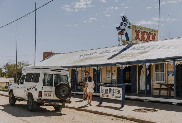 Due persone che entrano in un locale con un cane di cartone blu sul tetto al Blue Heeler Hotel, Kynuna, Queensland © Tourism and Events Queensland 