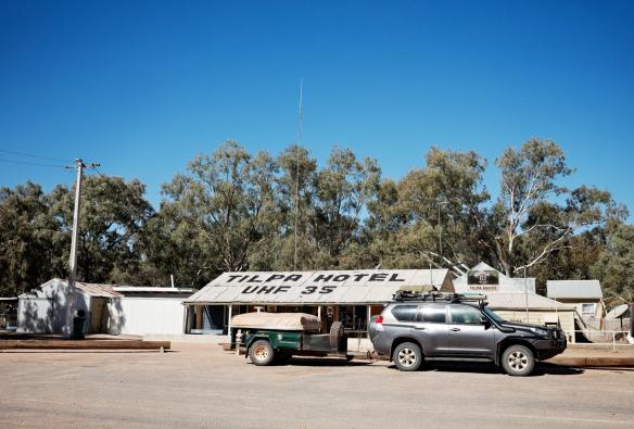 Un'auto con carrello parcheggiata all'esterno di un piccolo locale circondato dalla vegetazione del bushland al Tilpa Hotel, Tilpa, New South Wales © Destination NSW
