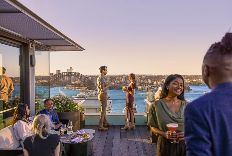 Ospiti che sorseggiano drink con la vista del Sydney Harbour dall'Aster, Sydney, New South Wales © Tourism Australia