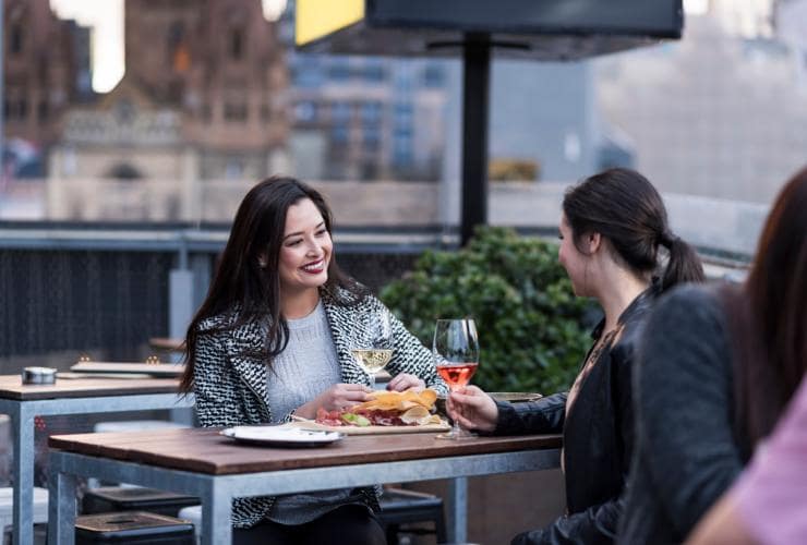 Due donne con calici di vino al Transit Rooftop Bar, Melbourne, Victoria © Visit Victoria 