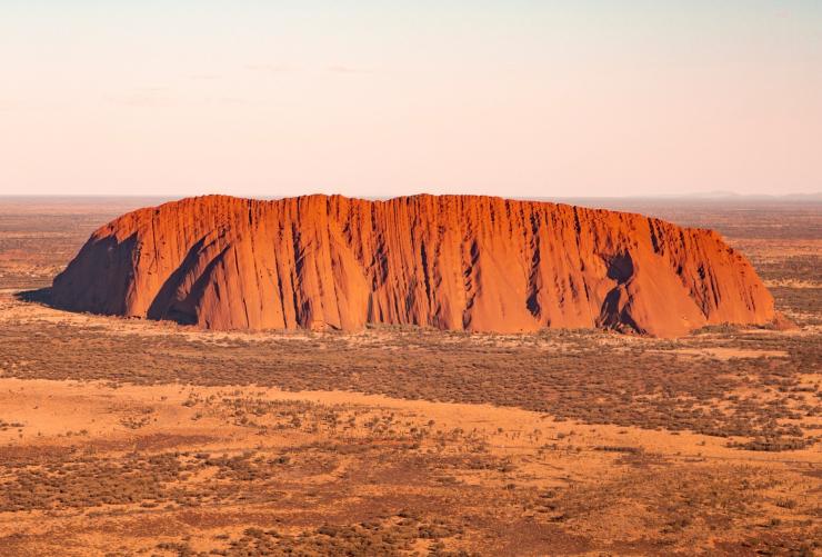 Vista aerea su un gigantesco monolite di roccia rossa in un paesaggio dell’outback, Uluṟu, Uluṟu-Kata Tjuṯa National Park, Northern Territory © Tourism Australia/Nicholas Kavo