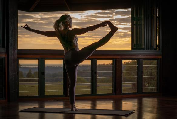 Donna in una posizione yoga su un balcone all'alba al Gwinganna Lifestyle Retreat, Tallebudgera Valley, Queensland © Gwinganna Lifestyle Retreat