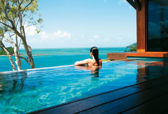 Donna appoggiata al bordo di una piscina a sfioro con vista sull'oceano al qualia, Hamilton Island, Queensland © Jason Loucas Photography