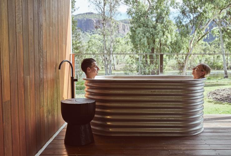Due persone si rilassano in una vasca da bagno sul balcone, Mt Mulligan Lodge, Mount Mulligan, Queensland © Jason Ierace