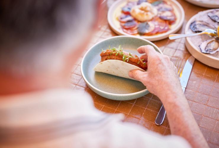 Una persona che mangia tacos e pesce fresco, Splendour Tailored Tours, Sydney, New South Wales © Tourism Australia