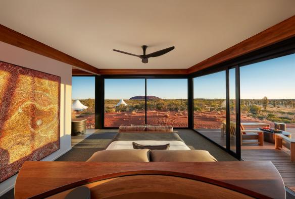 L’interno di una lussuosa camera d’albergo con vista sull’outback con un monolite di roccia rossa in lontananza, Longitude 131, Yulara, Northern Territory © Beckons Journeys