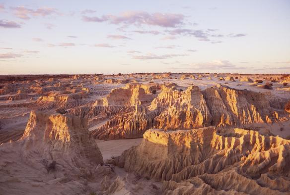 Una distesa rocciosa bianco sporco di argilla e dune di sabbia nel Mungo National Park al tramonto, New South Wales © Destination NSW