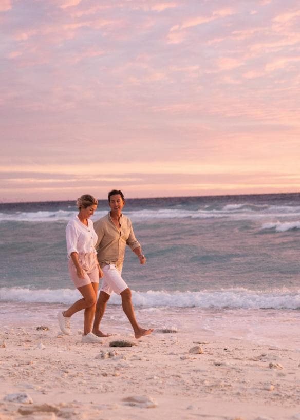 Coppia che passeggia lungo la spiaggia al tramonto presso il Lady Elliot Island Eco Resort, Grande Barriera Corallina, Queensland © Tourism and Events Queensland