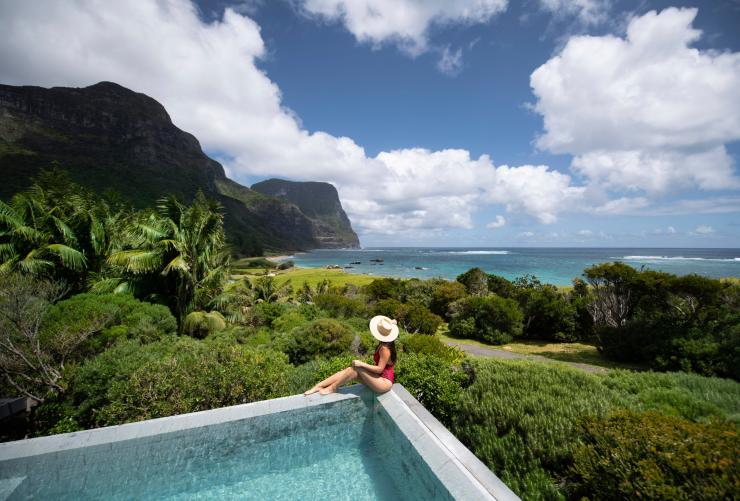 Donna seduta sul bordo di una piscina che guarda il paesaggio lussureggiante dal Capella Lodge su Lord Howe Island, New South Wales © Tom Archer