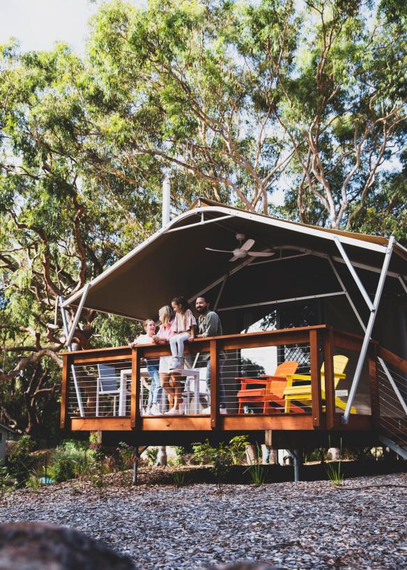 Una famiglia sul balcone di un bungalow con vista sul bushland, Port Stephens Koala Sanctuary, Port Stephens, New South Wales © Destination NSW 