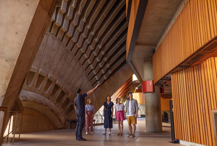 ニュー・サウス・ウェールズ州、シドニー、シドニー・オペラ・ハウス建物内で繊細な建築構造を見上げる観光客 © Tourism Australia
