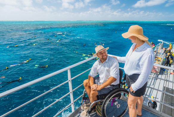 クイーンズランド州、グレートバリアリーフ、クイックシルバー・クルーズの船に乗る車椅子の男性とパートナー © Tourism and Events Queensland