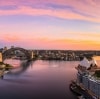 ニュー・サウス・ウェールズ州、シドニーの夕日の青、ピンク、金色の色彩を映したシドニー・ハーバーの上空からの眺め © Destination NSW