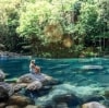 モスマン渓谷の岩石プールを臨む大きな岩に座る女性 © Tourism and Events Queensland