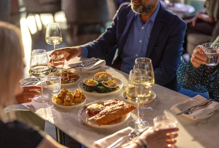 ニュー・サウス・ウェールズ州、シドニー、アスターにて、料理とワインが並んだテーブル © Tourism Australia