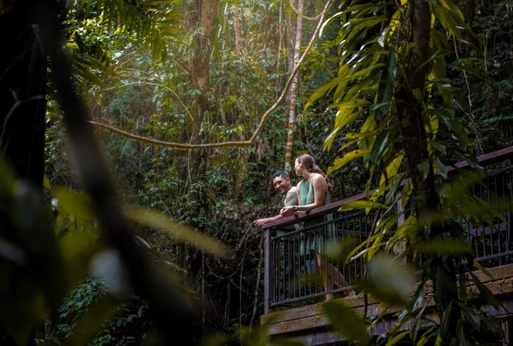クイーンズランド州、デインツリー、デインツリー・エコロッジ、熱帯雨林に囲まれたバルコニーにもたれる男性と女性 © Tourism and Events Queensland