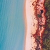 クイーンズランド州、ウィットサンデー諸島、ソルティー・ドッグ・アドベンチャー・ツアーに参加してビーチ沿いを歩くカップルの空撮 © Tourism and Events Queensland