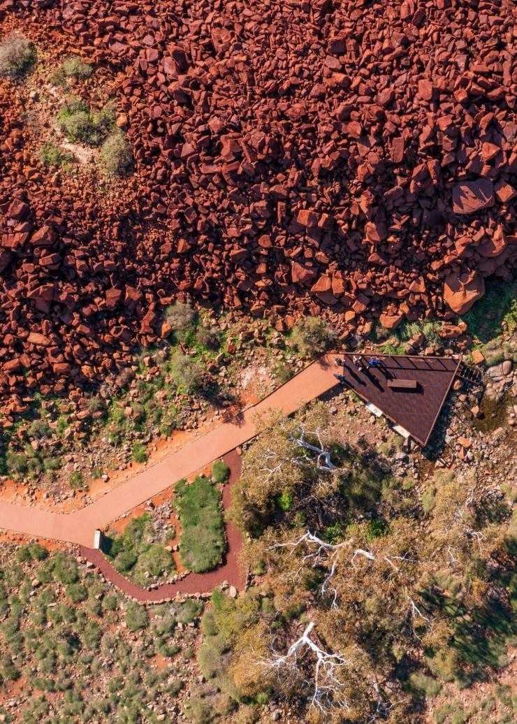 西オーストラリア州、ピルバラ、ムルジュガ・アボリジナル・コーポレーション、赤い岩の山々の間をうねる道の空撮 © Tourism Western Australia 