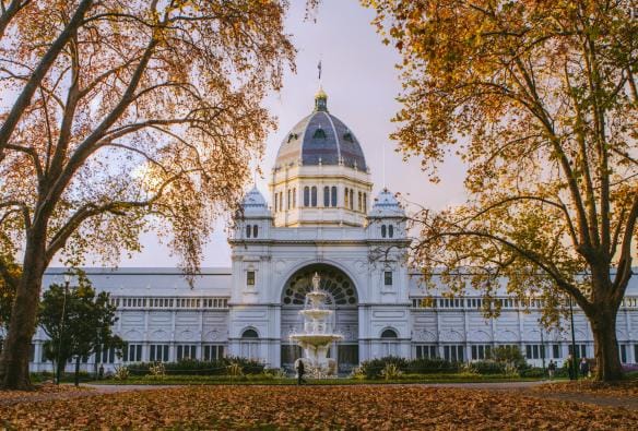 ビクトリア州、メルボルン、王立展示館とカールトン庭園、正面の噴水と秋の木々に囲まれた壮麗な白い建物 © Tourism Australia/Time Out Australia