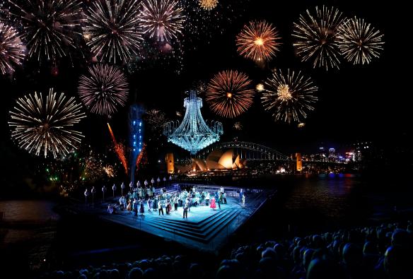시드니 하버 제방 위 무대에서 한다 오페라 온 시드니 하버의 공연이 펼쳐지고 있고 하늘에는 폭죽이 터지고 있는 광경, 시드니, 뉴사우스웨일스 © 호주정부관광청
