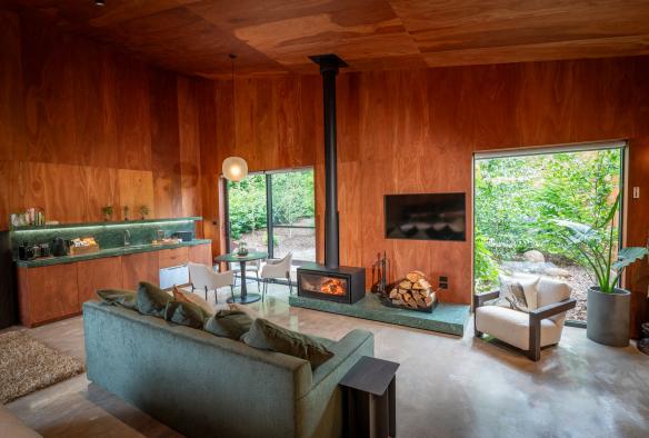녹색 가구와 목재 가구들 옆에 장작을 태우는 벽난로가 있는 데일즈포드의 사마디 리트리트 숙박시설의 내부 모습, 빅토리아 © 사마디 리트리트