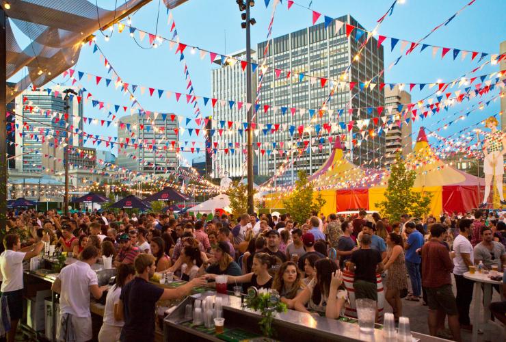 Một quán bar ngoài trời đầy ắp người bên dưới những dải cờ nhiều màu sắc tại Royal Croquet Club, Lễ hội Adelaide Fringe, Adelaide, Tiểu bang Nam Úc © South Australian Tourism Commission 