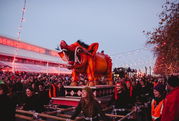 Đám đông đang theo dõi một cuộc diễu hành, trong đó một nhóm người đang khiêng một bức điêu khắc khổng lồ hình con lợn trong khuôn khổ Lễ hội Dark Mofo tại Hobart, Tasmania © Adam Gibson