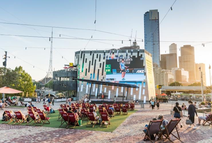Một rạp chiếu phim ngoài trời phát trận thi đấu quần vợt bên cạnh đường chân trời của thành phố trong mùa giải quần vợt Úc mở rộng, Melbourne, Victoria © Visit Victoria / Melbourne Convention Bureau 
