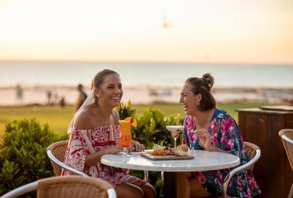 Hai người phụ nữ đang dùng bữa ngoài trời tại quán bar Sunset Bar, Bãi biển Cable, Thị trấn Broome, Tiểu bang Tây Úc © Tourism Australia
