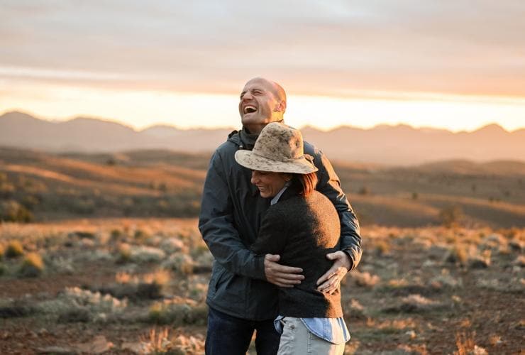 Một cặp đôi cười vui và ôm nhau tại thị trấn Blinman, Dãy núi Flinders, tiểu bang Nam Úc © Tourism Australia