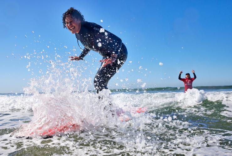 Một người lướt sóng mỉm cười trong khi cưỡi ngọn sóng tại Torquay Surf Academy, Cung đường Great Ocean Road, tiểu bang Victoria © Tourism Australia