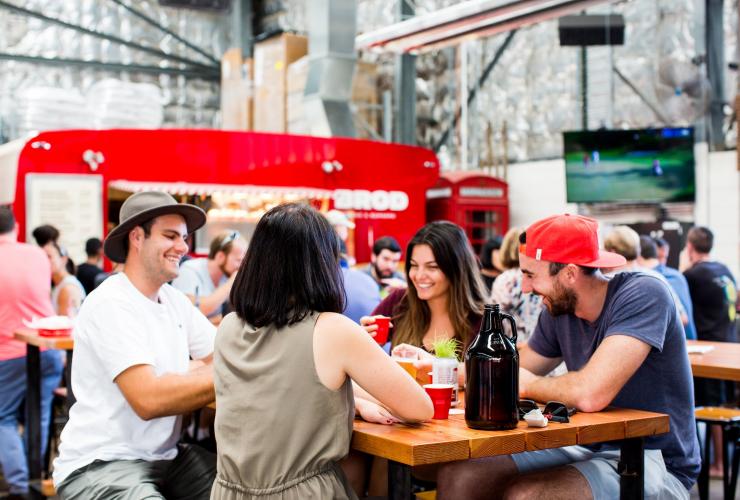 Một nhóm bạn quây quần bên bàn ăn tại quán bar Capital Brewing Co and Brodburger, Thành phố Canberra, Lãnh thổ Thủ đô Úc © Kara Rosenlund for VisitCanberra