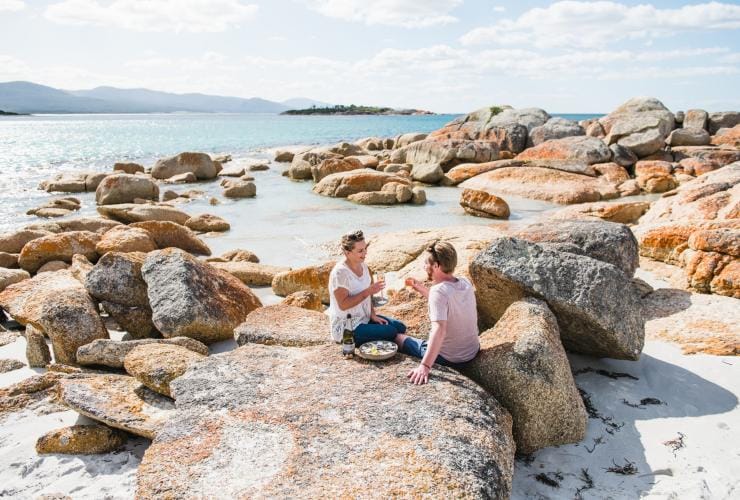 Một cặp đôi thưởng thức buổi dã ngoại trên những ghềnh đá gần bãi biển Waubs Bay, thị trấn Bicheno, tiểu bang Tasmania © Stu Gibson