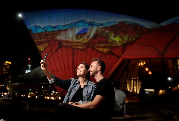 A couple taking a selfie in front of the Sydney Opera House at night, Sydney, New South Wales © Ken Leanfore
